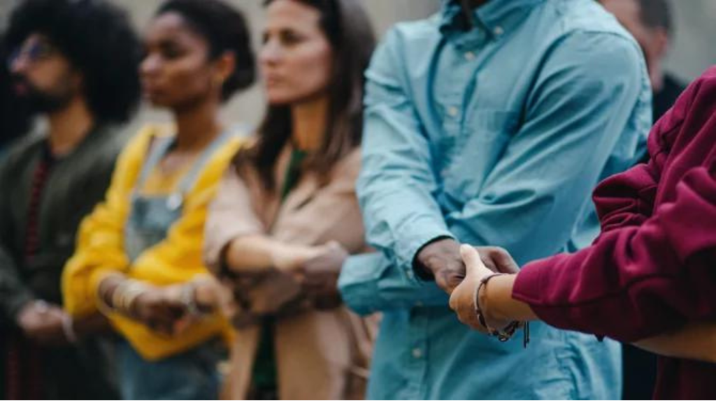 People standing in a line holding hands with each other.